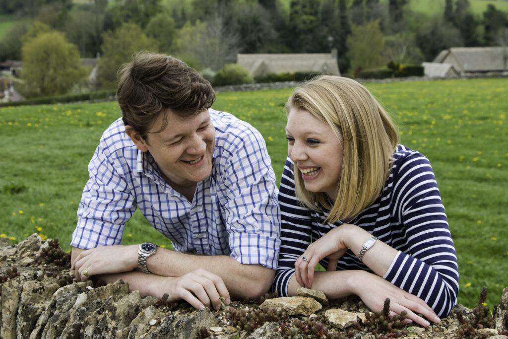engaged couple leaning on a wall laughing