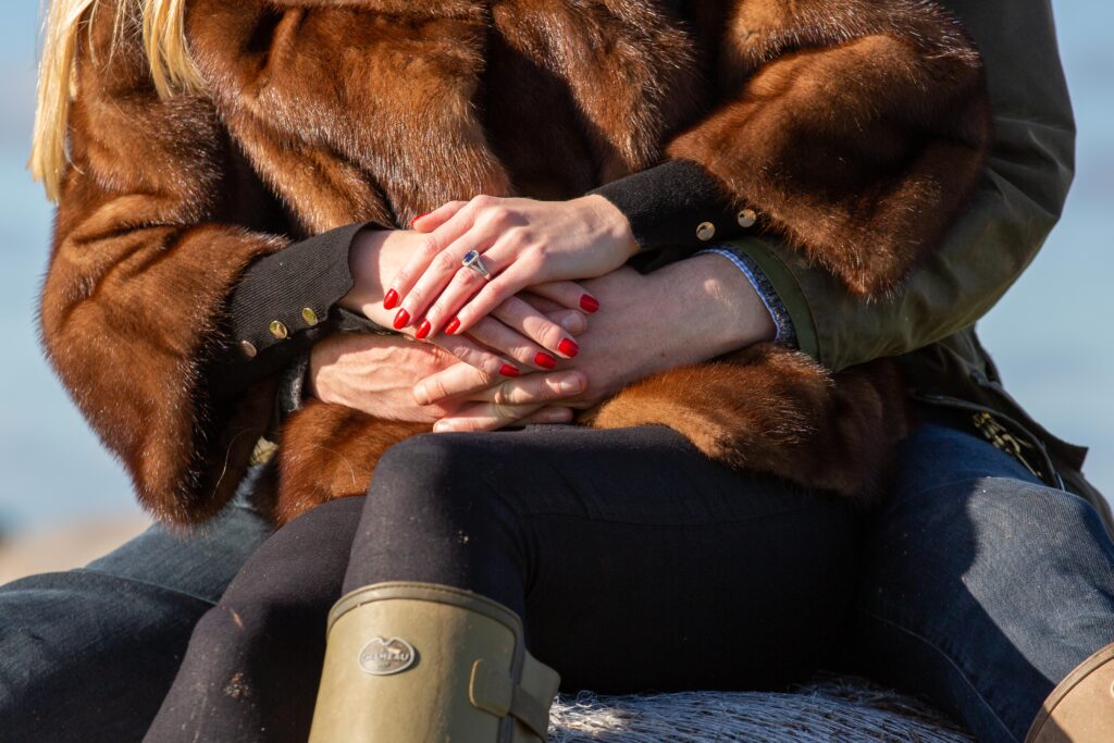 engaged couple sitting together hands clasped showing her engagement ring