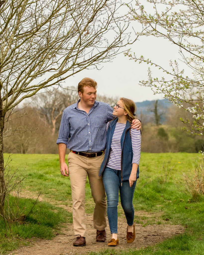 engaged couple walking in parkland arm in arm
