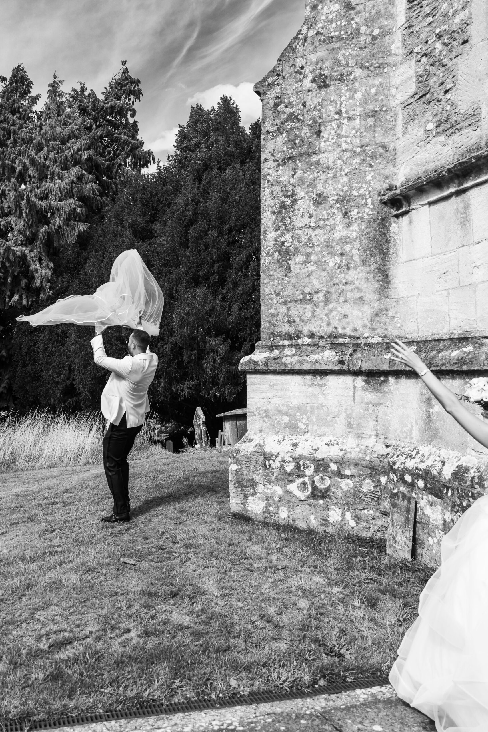 groom catching bride's veil as it tries to fly away