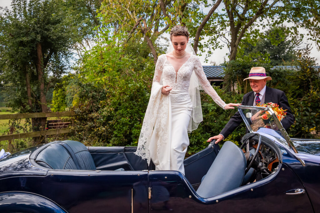 Bride being helped into her wedding car by her grandad